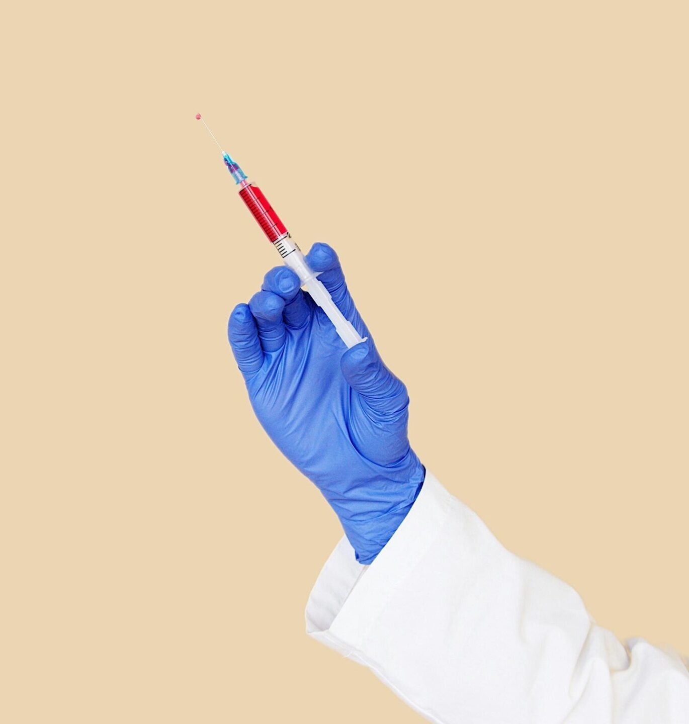 Unrecognizable healthcare worker holding a syringe with vaccine in a studio setting.